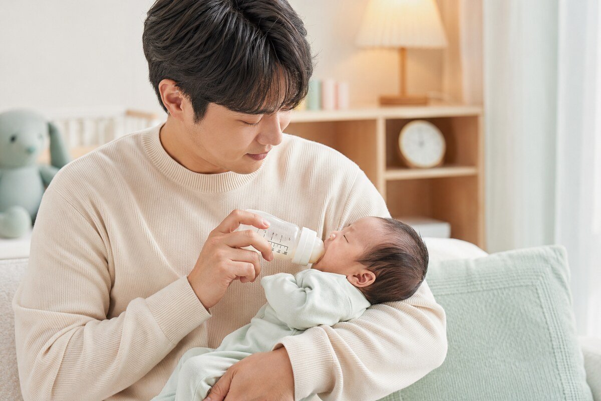재채기하는 신생아가 평소처럼 먹는지 반세운 자세로 수유하며 확인하는 아빠