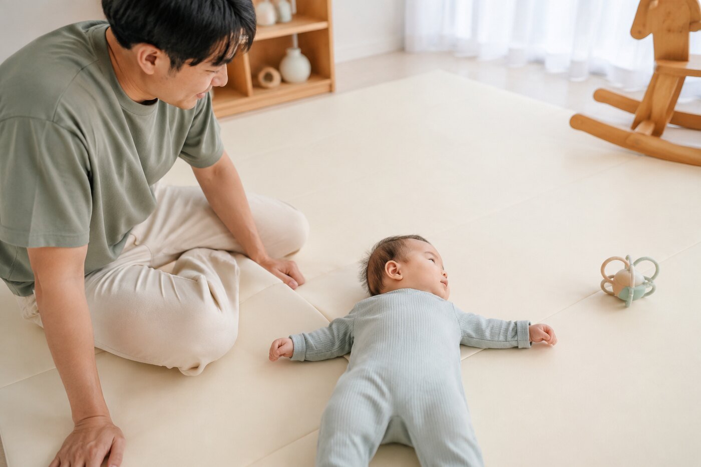 바닥에 누운 아기의 좌우 고개 돌리기와 양팔 움직임을 가까이서 관찰하는 아빠