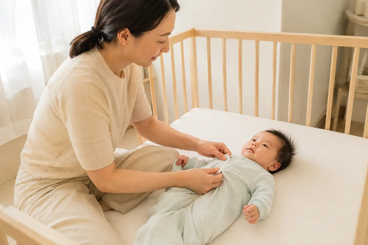 과열되지 않도록 신생아의 가벼운 옷차림을 조절하는 엄마